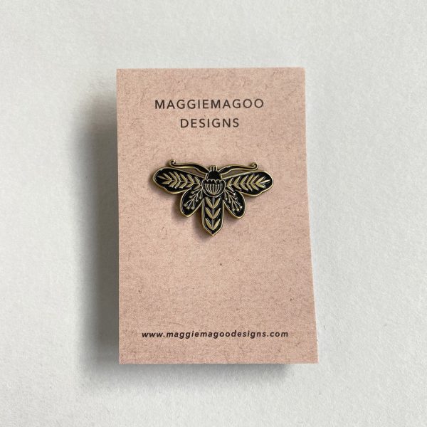 Enamel pin brooch, featuring a beautiful moth design, in black and gold metal.